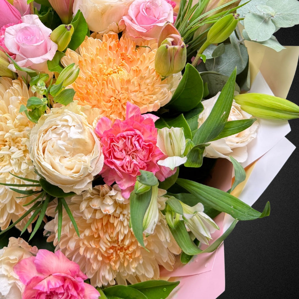 Close-up of a vibrant pastel Mother's Day bouquet featuring roses, chrysanthemums, and carnations.
