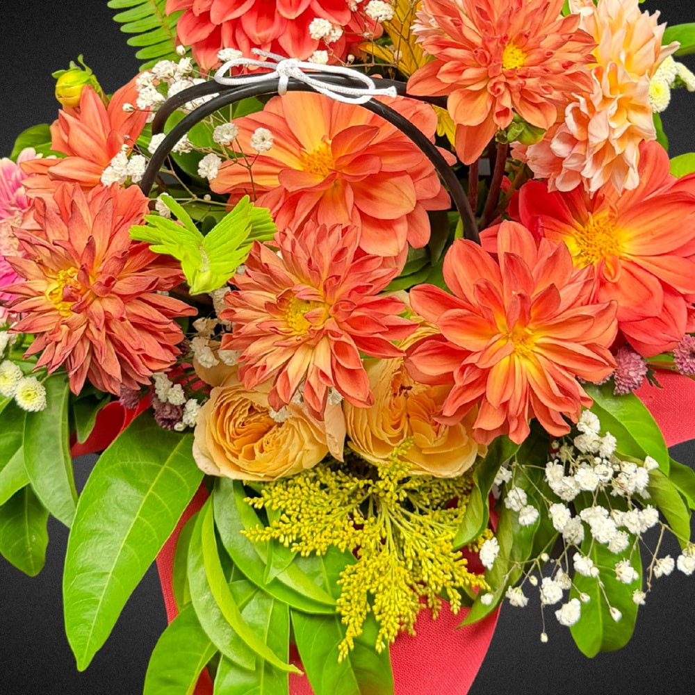 Close-up view of vibrant peach and coral dahlias and roses within the 'Eternal Embrace' Mother's Day bouquet, highlighting fresh petals and textures.