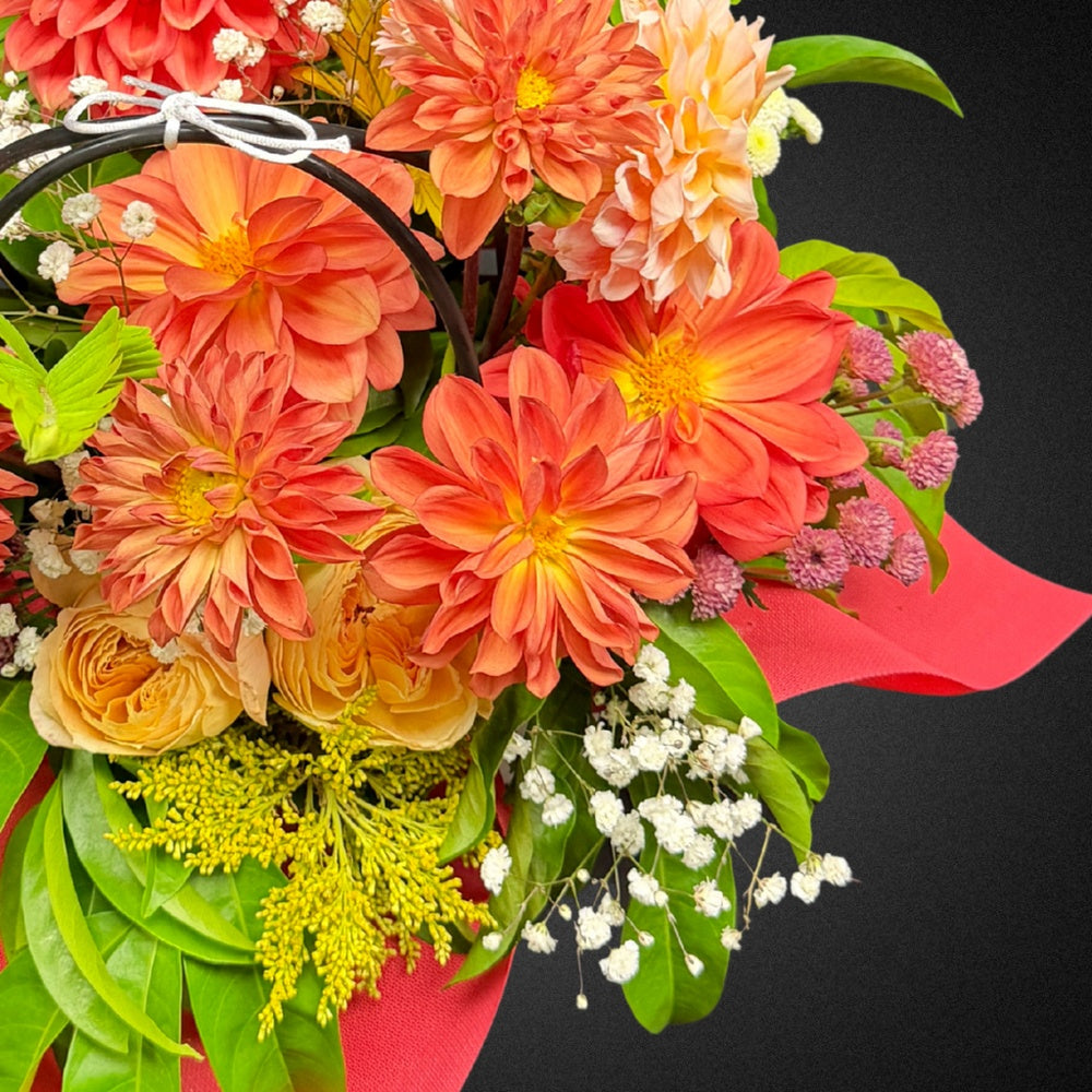 Close-up view of vibrant peach and coral dahlias and roses within the 'Eternal Embrace' Mother's Day bouquet, highlighting fresh petals and textures.