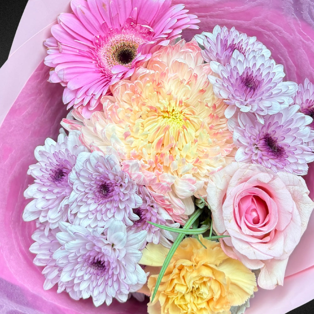 Close-up detail of 'The Everlasting Embrace' Mother's Day arrangement, showcasing the delicate textures of a soft pink rose, a creamy chrysanthemum, and the silvery hue of Dusty Miller foliage.