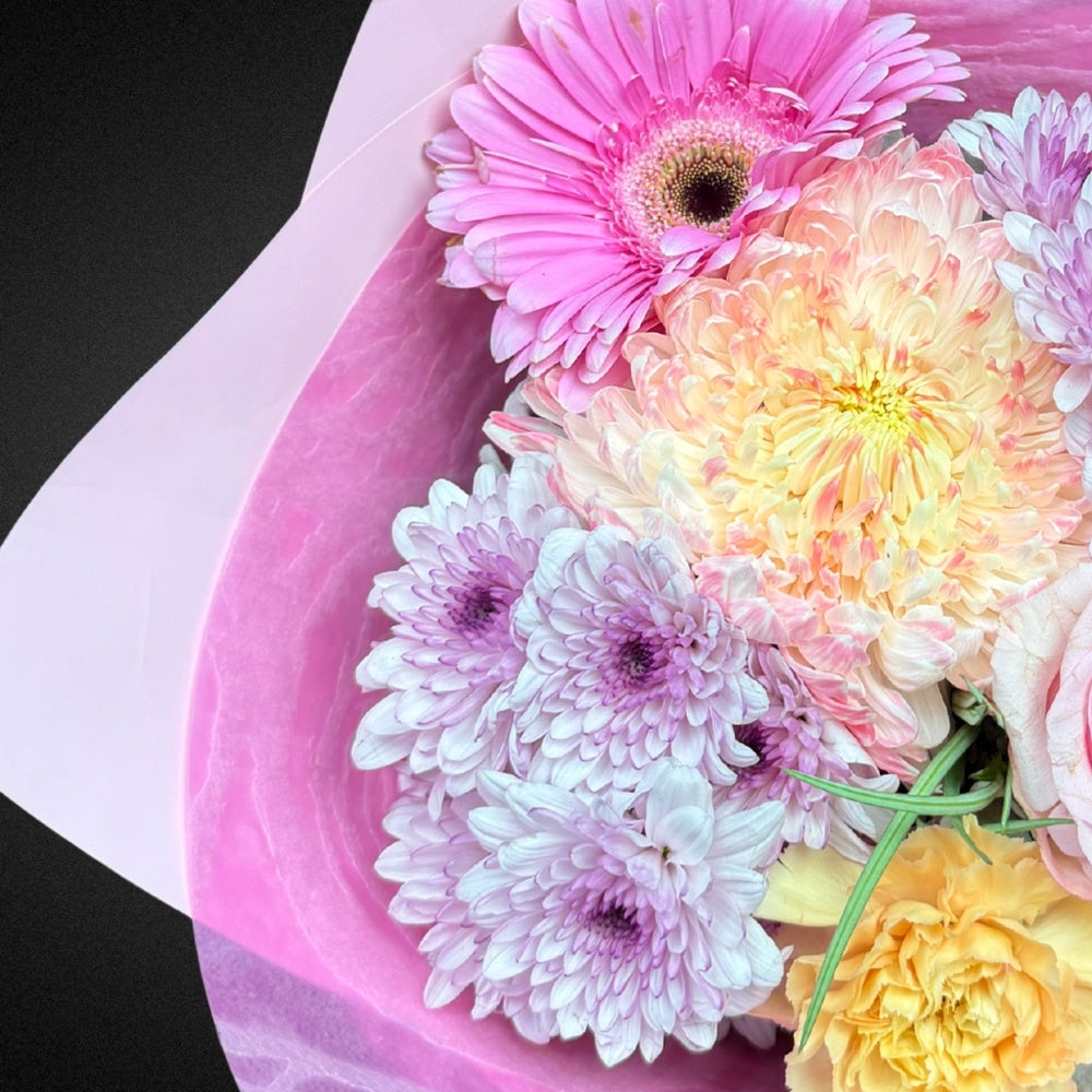 Close-up detail of 'The Everlasting Embrace' Mother's Day arrangement, showcasing the delicate textures of a soft pink rose, a creamy chrysanthemum, and the silvery hue of Dusty Miller foliage.