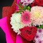 Close-up of premium bright roses, chrysanthemums, and carnations with pittosporum foliage in The Mum's Embrace Bouquet for Mother's Day.