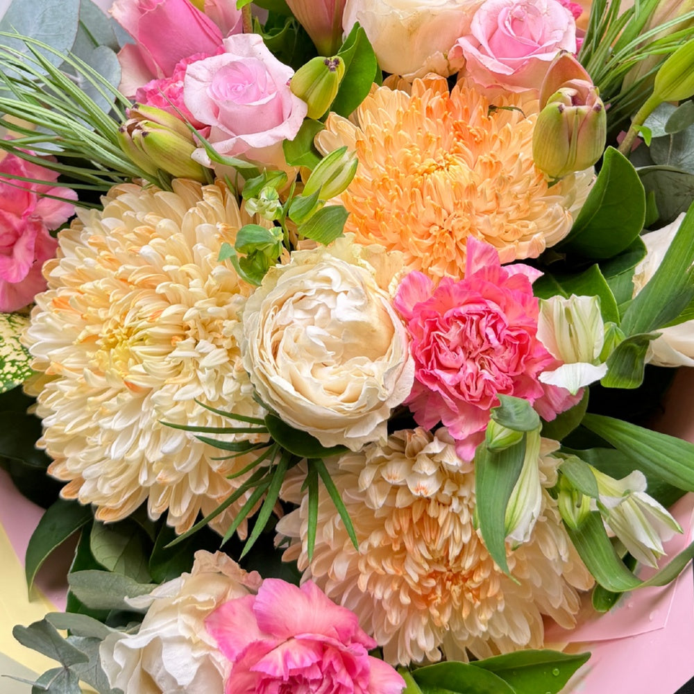 Close-up of a vibrant pastel Mother's Day bouquet featuring roses, chrysanthemums, and carnations.