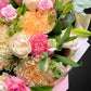 Close-up of a vibrant pastel Mother's Day bouquet featuring roses, chrysanthemums, and carnations.