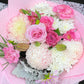 Close-up of a premium Mother's Day bouquet showcasing delicate pastel pink roses, cheerful white chrysanthemums, soft peach carnations, and silver-grey Dusty Miller leaves, highlighting the mixed pastel palette and fresh blooms.