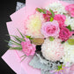 Close-up of a premium Mother's Day bouquet showcasing delicate pastel pink roses, cheerful white chrysanthemums, soft peach carnations, and silver-grey Dusty Miller leaves, highlighting the mixed pastel palette and fresh blooms.